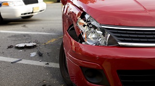 A red car with a damaged headlight after an accident